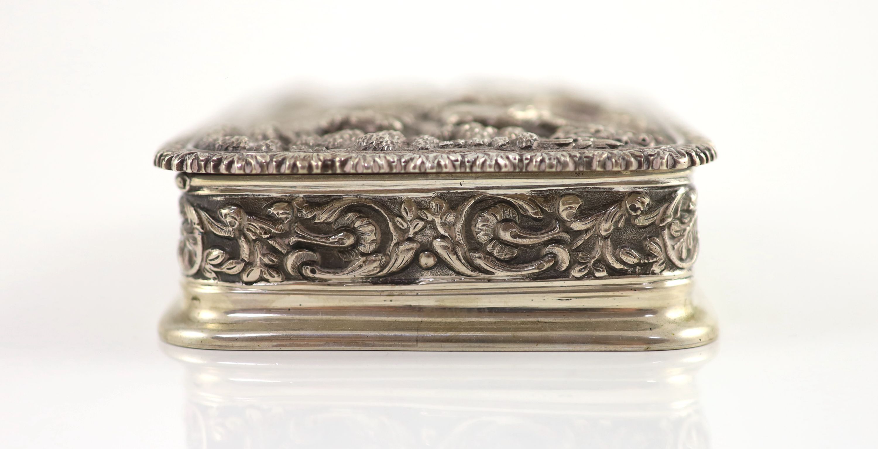 A 20th century Portuguese 833 standard silver rectangular box and cover, the lid cast and chased in high relief with travellers approaching a town,